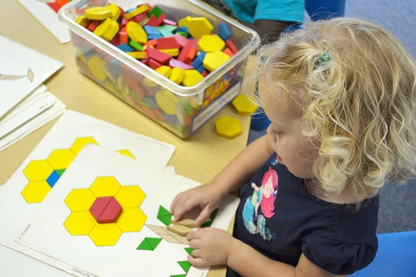Preschool child making art with block tiles