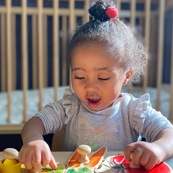 Toddler Explorers - educational toddler daycare at Learning Paths Academy - cute young girl playing with wooden vegetable shape blocks
