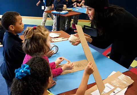 Teacher leading craft project following preschool curriculum